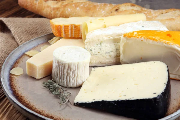 Rustik plaka üzerinde farklı peynir peynir tabağı.
