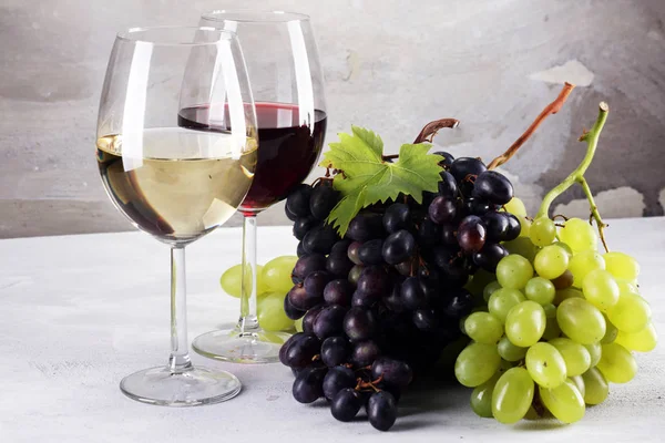 Kırmızı şarap ve beyaz şarap üzüm ve rustik zemin üzerine gözlük ile