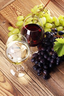Kırmızı şarap ve beyaz şarap üzüm ve rustik zemin üzerine gözlük ile