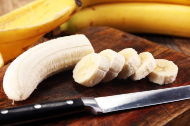 A banch of bananas and a sliced banana over a table clipart