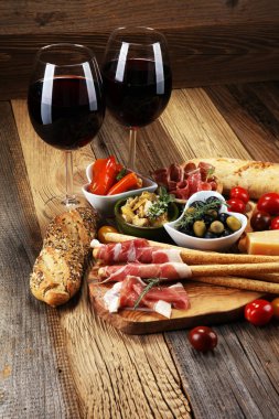 İtalyan antipasti şarap aperatifler küme. Peynir çeşitli, Akdeniz zeytin, crudo, Prosciutto di Parma, salam ve ahşap grunge arka plan üzerinde bardaklarda şarap