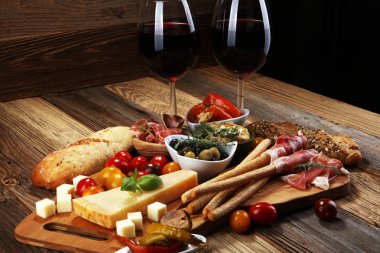İtalyan antipasti şarap aperatifler küme. Peynir çeşitli, Akdeniz zeytin, crudo, Prosciutto di Parma, salam ve ahşap grunge arka plan üzerinde bardaklarda şarap