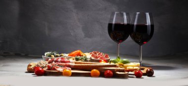 İtalyan antipasti şarap aperatifler küme. Peynir çeşitli, Akdeniz zeytin, crudo, Prosciutto di Parma, salam ve taş grunge arka plan üzerinde bardaklarda şarap