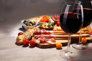 İtalyan antipasti şarap aperatifler küme. Peynir çeşitli, Akdeniz zeytin, crudo, Prosciutto di Parma, salam ve taş grunge arka plan üzerinde bardaklarda şarap