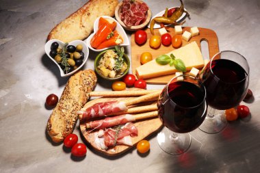 İtalyan antipasti şarap aperatifler küme. Peynir çeşitli, Akdeniz zeytin, crudo, Prosciutto di Parma, salam ve taş grunge arka plan üzerinde bardaklarda şarap
