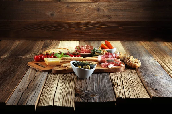 意大利开胃小菜酒小吃套装 奶酪品种 地中海橄榄 Crudo 意大利熏火腿 意大利香肠和葡萄酒在木制垃圾背景玻璃上 — 图库照片
