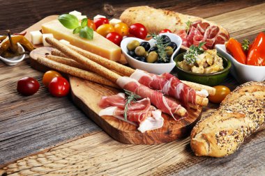 İtalyan antipasti şarap aperatifler küme. Peynir çeşitli, Akdeniz zeytin, crudo, Prosciutto di Parma, salam ve ahşap grunge arka plan üzerinde bardaklarda şarap