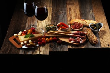 İtalyan antipasti şarap aperatifler küme. Peynir çeşitli, Akdeniz zeytin, crudo, Prosciutto di Parma, salam ve ahşap grunge arka plan üzerinde bardaklarda şarap