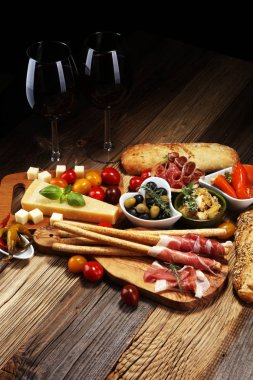 İtalyan antipasti şarap aperatifler küme. Peynir çeşitli, Akdeniz zeytin, crudo, Prosciutto di Parma, salam ve ahşap grunge arka plan üzerinde bardaklarda şarap