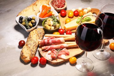 İtalyan antipasti şarap aperatifler küme. Peynir çeşitli, Akdeniz zeytin, crudo, Prosciutto di Parma, salam ve taş grunge arka plan üzerinde bardaklarda şarap