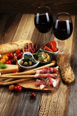 İtalyan antipasti şarap aperatifler küme. Peynir çeşitli, Akdeniz zeytin, crudo, Prosciutto di Parma, salam ve ahşap grunge arka plan üzerinde bardaklarda şarap