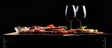 İtalyan antipasti şarap aperatifler küme. Peynir çeşitli, Akdeniz zeytin, crudo, Prosciutto di Parma, salam ve ahşap grunge arka plan üzerinde bardaklarda şarap