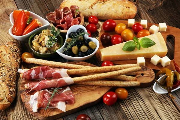 İtalyan antipasti şarap aperatifler küme. Peynir çeşitli, Akdeniz zeytin, crudo, Prosciutto di Parma, salam ve ahşap grunge arka plan üzerinde bardaklarda şarap