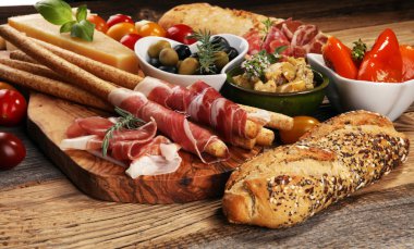 İtalyan antipasti şarap aperatifler küme. Peynir çeşitli, Akdeniz zeytin, crudo, Prosciutto di Parma, salam ve ahşap grunge arka plan üzerinde bardaklarda şarap