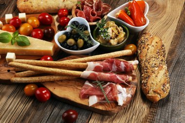 İtalyan antipasti şarap aperatifler küme. Peynir çeşitli, Akdeniz zeytin, crudo, Prosciutto di Parma, salam ve ahşap grunge arka plan üzerinde bardaklarda şarap
