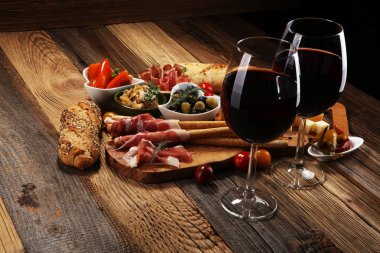 İtalyan antipasti şarap aperatifler küme. Peynir çeşitli, Akdeniz zeytin, crudo, Prosciutto di Parma, salam ve ahşap grunge arka plan üzerinde bardaklarda şarap