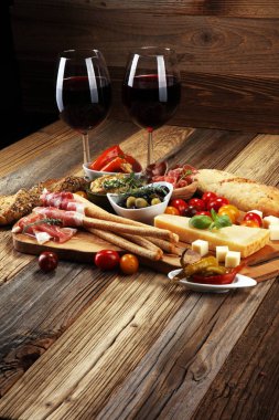 İtalyan antipasti şarap aperatifler küme. Peynir çeşitli, Akdeniz zeytin, crudo, Prosciutto di Parma, salam ve ahşap grunge arka plan üzerinde bardaklarda şarap
