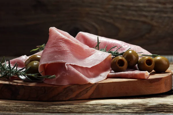 Sliced ham on wooden cutting board. Fresh prosciutto. Pork ham sliced.
