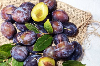 Erik rustik arka plan üzerinde. Mavi erik meyve yarısı. Yaprakları ile birçok güzel Erik.