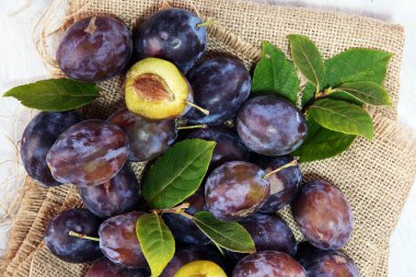 Erik rustik arka plan üzerinde. Mavi erik meyve yarısı. Yaprakları ile birçok güzel Erik.