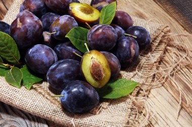 Erik rustik arka plan üzerinde. Mavi erik meyve yarısı. Yaprakları ile birçok güzel Erik.