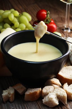 Bir kış akşamında gurme İsviçre fondü yemek peynir fondü iki çatal bir lokali veya restoran arkasında ekmek ve beyaz şarap daldırma ile ısıtmalı bir sürahi yanında bir gemide çeşitli peynir ile