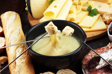 Bir kış akşamında gurme İsviçre fondü yemek peynir fondü iki çatal bir lokali veya restoran arkasında ekmek ve beyaz şarap daldırma ile ısıtmalı bir sürahi yanında bir gemide çeşitli peynir ile