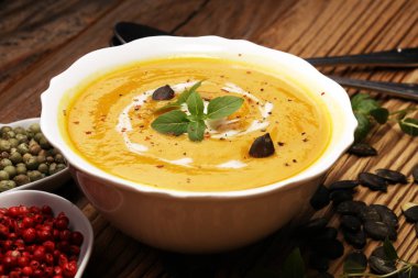 Ahşap arka plan üzerinde krem ve kabak çekirdeği ile kavrulmuş kabak ve havuç çorbası