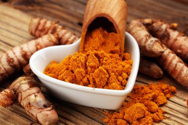 Taşra arka planında zerdeçal tozu ve taze zerdeçal..