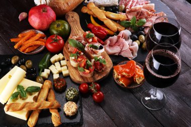 İtalyan antipasti şarap aperatifler küme. Peynir çeşitli, Akdeniz zeytin, turşu, Prosciutto di Parma, domates, enginar ve şarap gözlük siyah grunge arka plan üzerinde