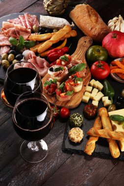 İtalyan antipasti şarap aperatifler küme. Peynir çeşitli, Akdeniz zeytin, turşu, Prosciutto di Parma, domates, enginar ve şarap gözlük siyah grunge arka plan üzerinde