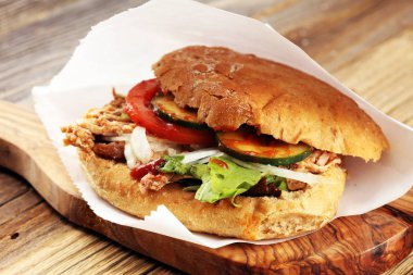 Çekti domuz sandviç Barbekü sosu, lahana ve ahşap masa üzerinde turşu ile.