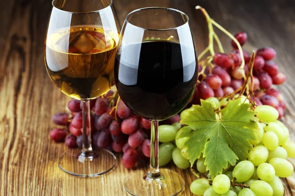 White wine and red wine in a glass with fall grapes on rustic background