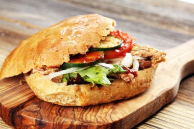 Çekti domuz sandviç Barbekü sosu, lahana ve ahşap masa üzerinde turşu ile.