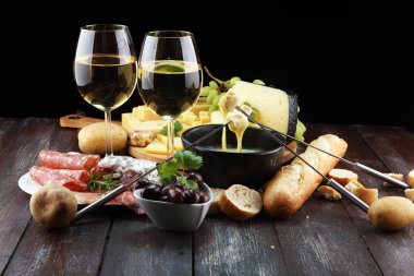 Bir kış akşamında gurme İsviçre fondü yemek peynir fondü iki çatal bir lokali veya restoran arkasında ekmek ve beyaz şarap daldırma ile ısıtmalı bir sürahi yanında bir gemide çeşitli peynir ile