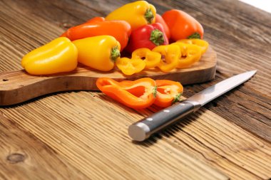 Taze kırmızı, sarı ve turuncu biber ahşap arka plan üzerinde. Yaş sebze