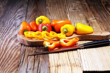 Taze kırmızı, sarı ve turuncu biber ahşap arka plan üzerinde. Yaş sebze