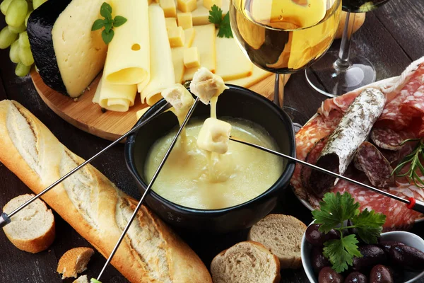 美食瑞士火锅晚餐在一个冬天的晚上 与各种奶酪一起在一个板上的一个加热锅奶酪火锅与两个叉子蘸面包和白葡萄酒背后的酒馆或餐厅 — 图库照片