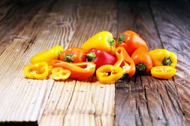 Taze kırmızı, sarı ve turuncu biber ahşap arka plan üzerinde. Yaş sebze