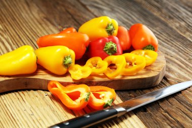 Taze kırmızı, sarı ve turuncu biber ahşap arka plan üzerinde. Yaş sebze