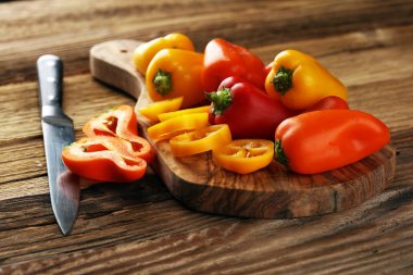 Taze kırmızı, sarı ve turuncu biber ahşap arka plan üzerinde. Yaş sebze