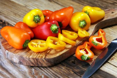 Taze kırmızı, sarı ve turuncu biber ahşap arka plan üzerinde. Yaş sebze