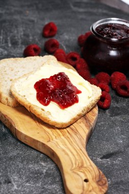 Kahvaltı veya brunch için ev yapımı ahududu reçel veya marmelat rustik tablo tost ekmeği tereyağı ile hizmet.