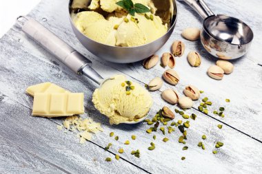 Fıstıklı dondurma kaşık ile kıyılmış fındık ve beyaz rustik bir arka plan üzerinde çikolata