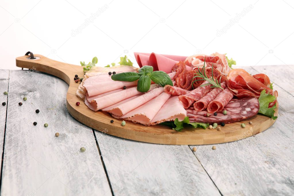 Food tray with delicious salami, pieces of sliced ham, sausage and salad. Meat platter with selection