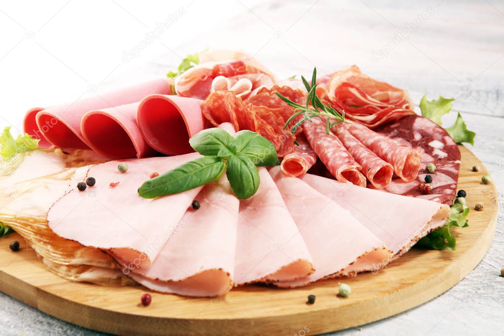 Food tray with delicious salami, pieces of sliced ham, sausage and salad. Meat platter with selection