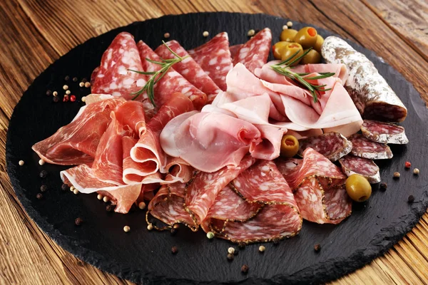 Jambon, pastırma, salam ve sosis ahşap arka plan üzerinde mermer kesme tahtası. Et tabağı