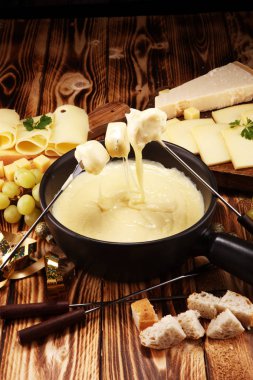 Bir kış akşamında gurme İsviçre fondü yemek peynir fondü iki çatal bir lokali veya restoran ekmek daldırma ile ısıtmalı bir sürahi yanında bir gemide çeşitli peynir ile