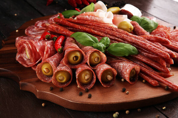 Поднос с вкусной салями, кусочки нарезанной ветчины крудо, колбасы и базилика. Мясо блюдо с выбором
.