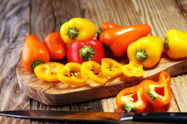 Taze kırmızı, sarı ve turuncu biber ahşap arka plan üzerinde. Yaş sebze